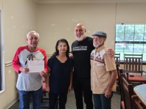 Mr. Kevin Sevin, Co-Owner of the Just4Him Haircut Franchise presents a $5,000 contribution to former Daigleville students towards the United Houma Nation's efforts to raise the funds to purchase the historic site to preserve tribal history.